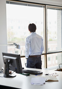 Rear view of mature businessman standing looking out through window