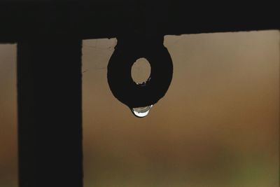 Close-up of water drop hanging from pipe