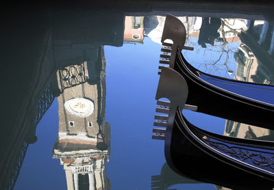 Reflection of clock tower in canal with gondola