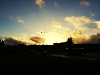 Silhouette city street against sky during sunset