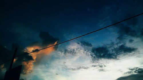 Low angle view of power lines against cloudy sky