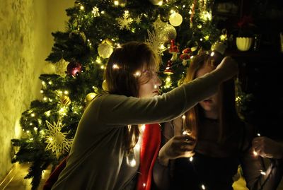 People in illuminated christmas tree