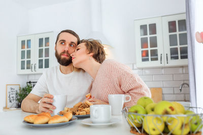 Man and woman holding coffee cup on table at home