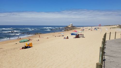 Scenic view of beach against cloudy sky on sunny day