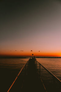 Pier over sea against sky during sunset