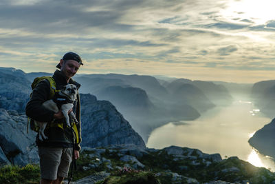 Side view of man standing on mountain against sky during sunset