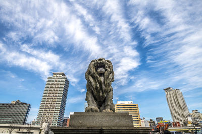 Low angle view of statue against buildings in city against sky