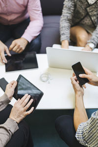 Midsection of businesspeople using technologies at table in office