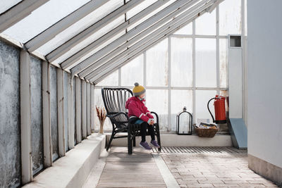 Girl sitting on a chair in a green house in winter