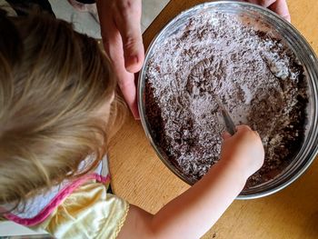 High angle view of girl with mother preparing food on table