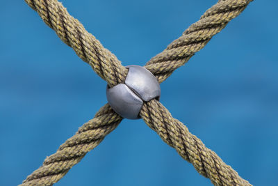 Close-up of crossed ropeagainst blue background