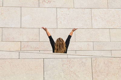 Rear view of woman standing against tiled wall