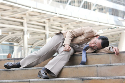 Full length of exhausted businessman lying on steps