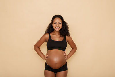 Portrait of pregnant woman standing against white background