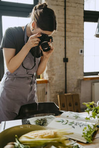 Food stylist photographing through digital camera while working in studio