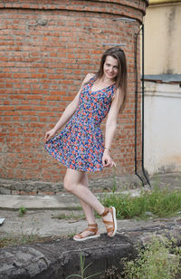 Full length portrait of young woman standing on wall