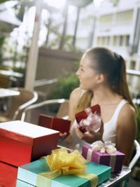 Smiling woman sitting by gifts in restaurant