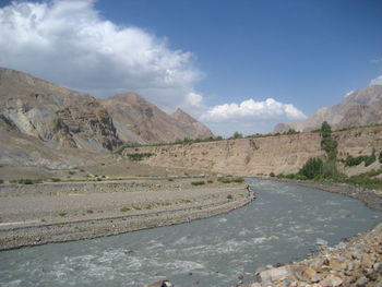 Scenic view of road by mountains against sky