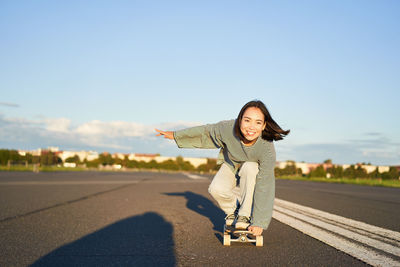 Portrait of young woman standing against sky