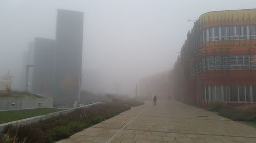 Man in city against sky during foggy weather