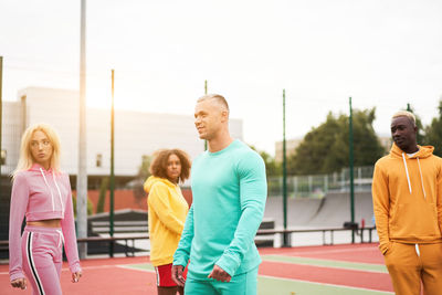 Friends standing on sports court against sky