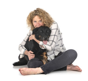 Portrait of teenage girl sitting with dog against white background