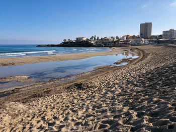 Scenic view of beach by buildings against clear sky