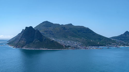 Scenic view of sea and mountains against clear blue sky