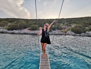 Full length of woman standing in sea against sky