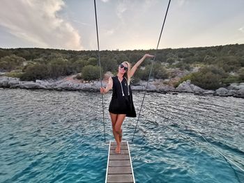 Full length of woman standing in sea against sky