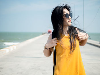 Young woman wearing sunglasses while standing by sea