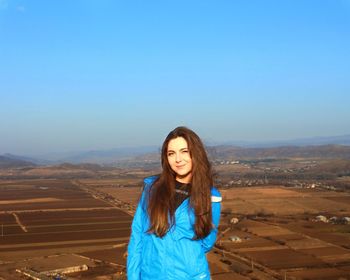 Portrait of beautiful young woman standing against clear sky