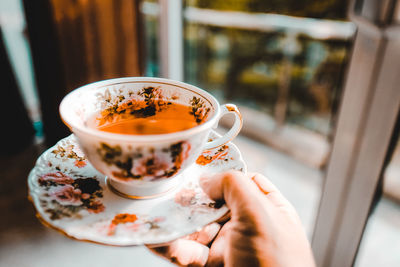 Cropped hand holding coffee cup at home