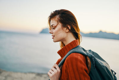 Portrait of young woman looking at sea against sky