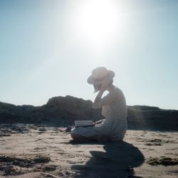 Side view of a woman reading book on beach