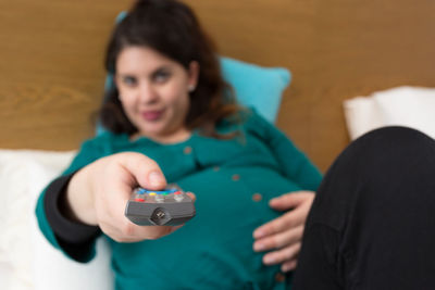 Portrait of woman holding mobile phone while sitting on sofa