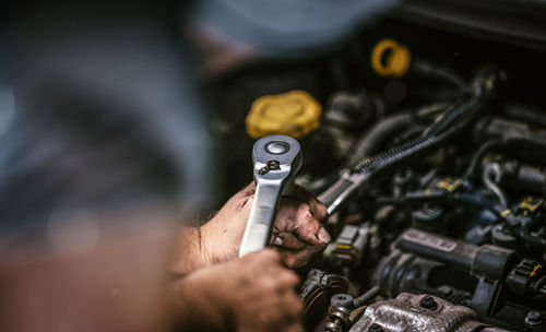 Cropped hands of mechanic repairing car engine