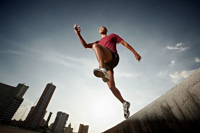 Low angle view of man jumping against sky