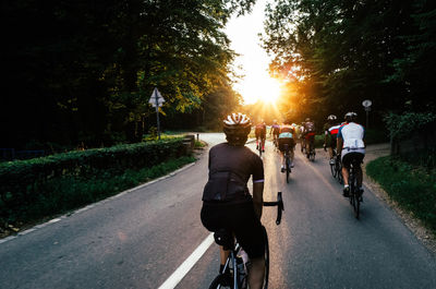 Rear view of people riding bicycle on road against sky
