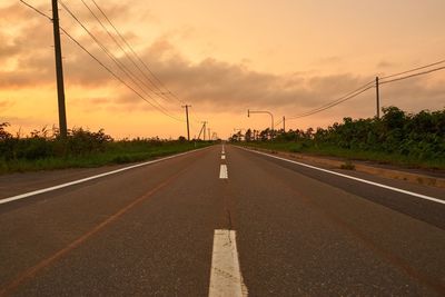 Empty road against cloudy sky during sunset