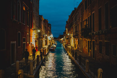 A canal in venice italy amidst buildings in city at night