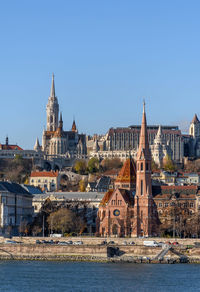 Buildings in city against clear blue sky