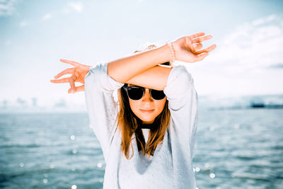 Young woman wearing sunglasses in sea against sky