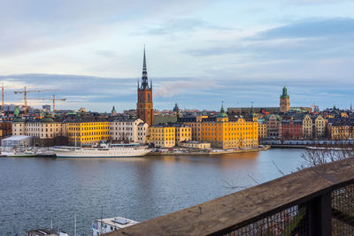 Buildings at waterfront against cloudy sky