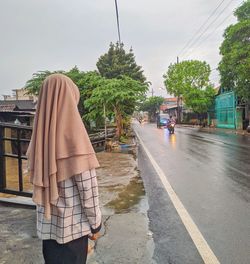 Rear view of people walking on wet road in rainy season