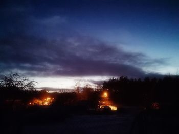 Silhouette trees on field against sky at night