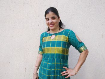 Portrait of smiling woman standing against wall