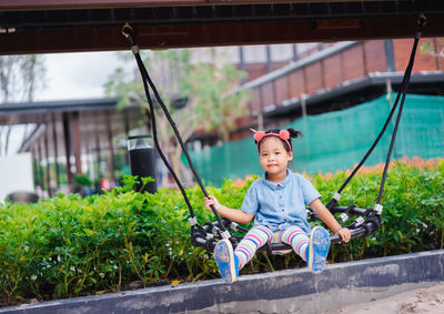 Full length portrait of cute girl swinging at park