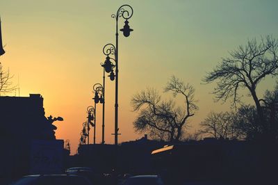 Low angle view of silhouette lamp posts against sky during sunset