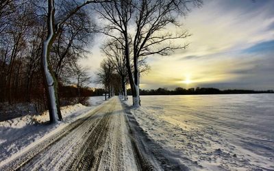 Snow covered road passing through field